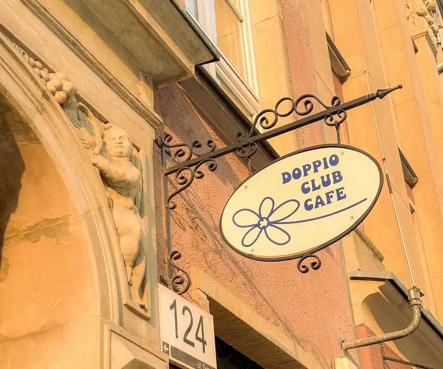 Owalny szyld Doppio Club Cafe nad wejściem do kamienicy nr 124