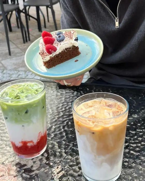 Matcha z owocami i mrożona kawa obok kawałka ciasta